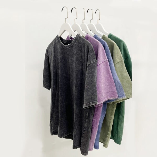 Five custom acid wash oversized cotton t-shirts in various colors hanging on hangers.