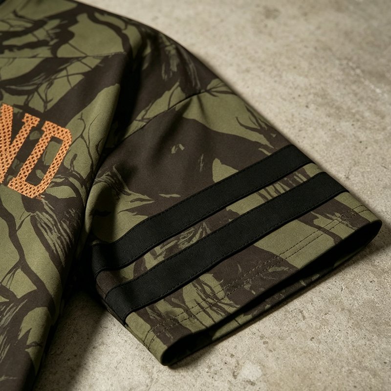 Close-up of a camo print jersey sleeve with black stripes and orange text