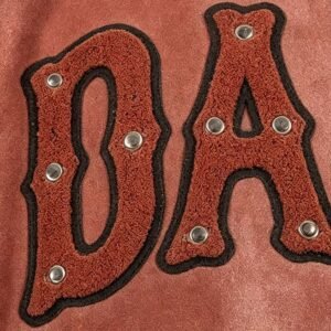 Close-up of red chenille applique letters 'DA' on a jacket.