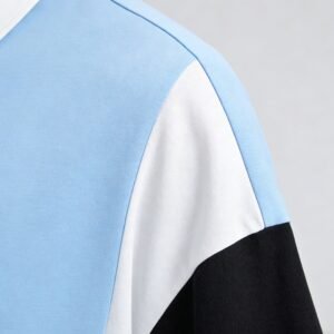 Close-up of a custom color-block polo shirt with blue, white, and black panels.