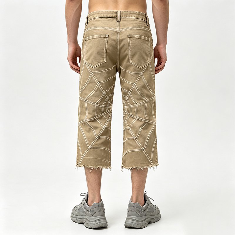 Man wearing tan cropped denim jeans with spiderweb stitching.