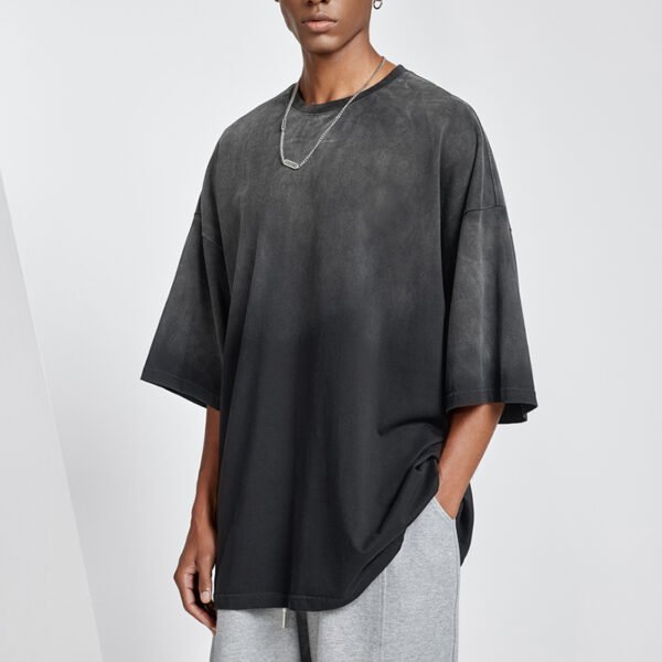 Man wearing a dark gray oversized heavyweight t-shirt with an acid wash effect.