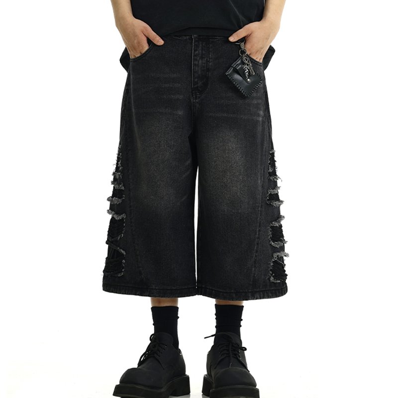 Man wearing distressed black denim long shorts with ripped details
