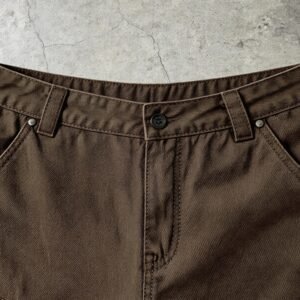 Close-up of distressed brown capri pants with button fly and belt loops.