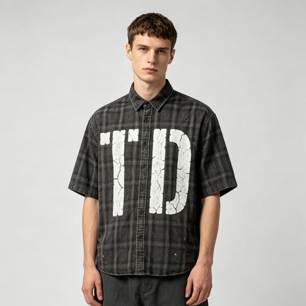Custom Distressed Plaid Graphic Short-Sleeve Shirt - Style A82303 Man wearing a dark gray plaid short-sleeve shirt with distressed white 'TD' graphic.