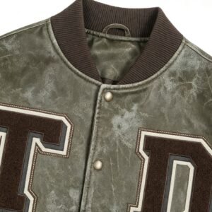 Close-up of a custom olive distressed varsity jacket with embroidered letters