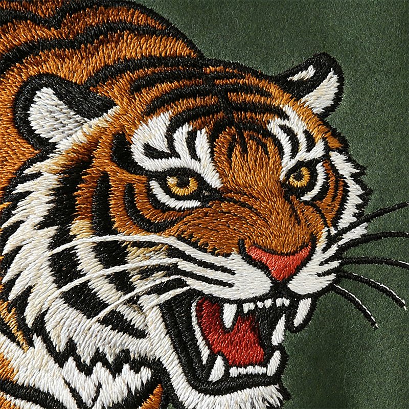 Close-up of an embroidered tiger face on a green varsity jacket.