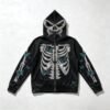 Black distressed full-zip hooded jacket with skeleton and butterfly rhinestone graphics.