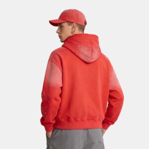 Man wearing a red and orange gradient washed rhinestone applique pullover hoodie