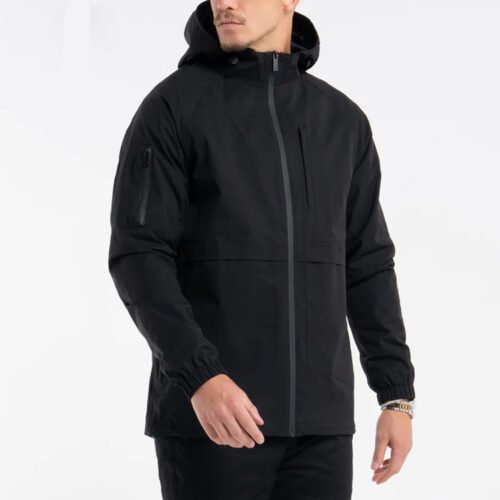 Custom Men's Hooded Technical Shell Jacket | VWW-JKT-5187 - Style 518731 Man wearing a black hooded technical jacket with zippered pockets.