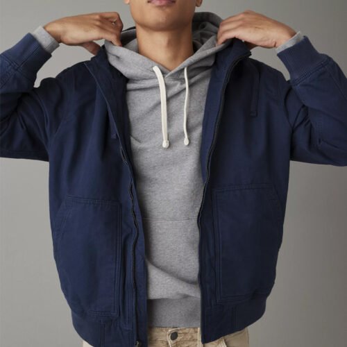 Man wearing a navy blue hooded utility windbreaker jacket over a grey hoodie.