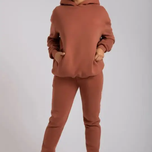 Woman wearing a rust-colored minimalist hoodie and jogger set