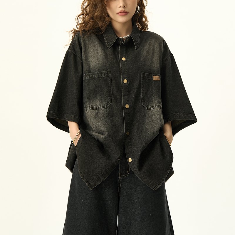 Woman wearing a black washed denim oversized short-sleeve collared shirt.