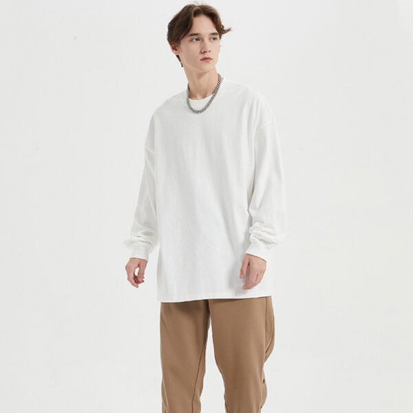 Man wearing a white oversized long-sleeve crew neck t-shirt.
