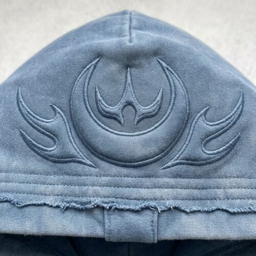 Custom Washed Padded Embroidered Raw-Edge Hoodie - Style 764517 Close-up of a blue washed hoodie with embroidered graphic on the hood