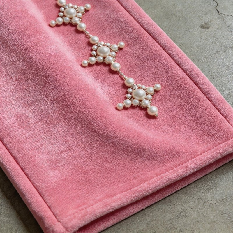 Pink velvet cropped pants with pearl embellishments.