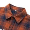 Close-up of an orange and navy plaid shirt collar and buttons