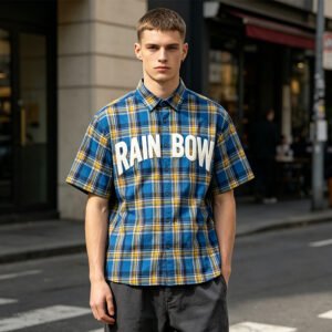 Man wearing a blue and yellow plaid short-sleeve shirt with RAINBOW text