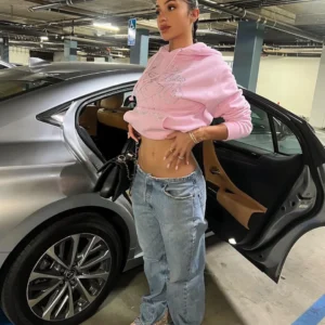 Woman wearing a pink rhinestone graphic pullover hoodie and jeans