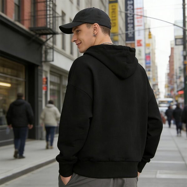 Man wearing a black pullover hoodie with a rhinestone spider motif