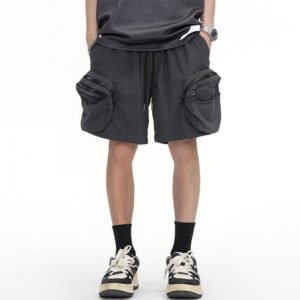 Man wearing dark grey utility cargo shorts with multiple zippered pockets.