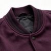 Close-up of a wine red varsity jacket collar with black stripes.