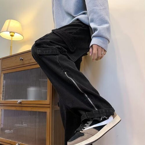 Close-up of black washed cargo jeans with zipper details on the leg.