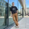 Man in black washed graphic streetwear t-shirt and brown pants