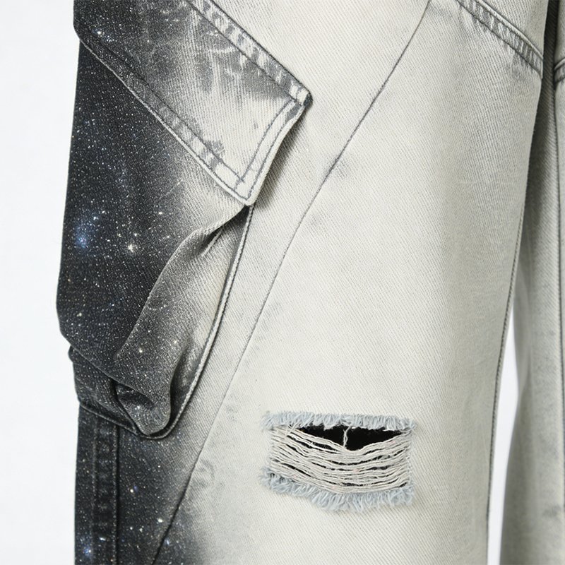 Close-up of light grey cargo pants with a galaxy print contrast panel and ripped detail.