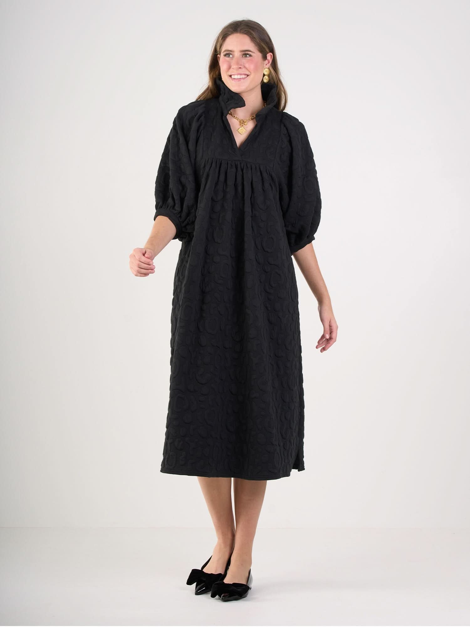 Woman wearing a black textured midi dress with puff sleeves