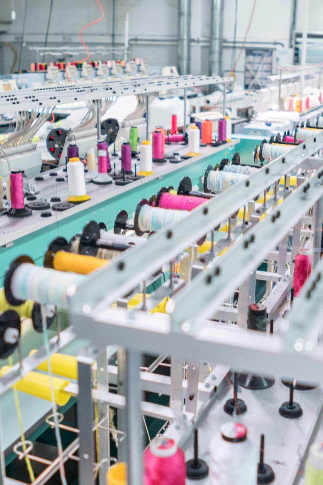 Close-up of industrial sewing machines and spools of colorful thread