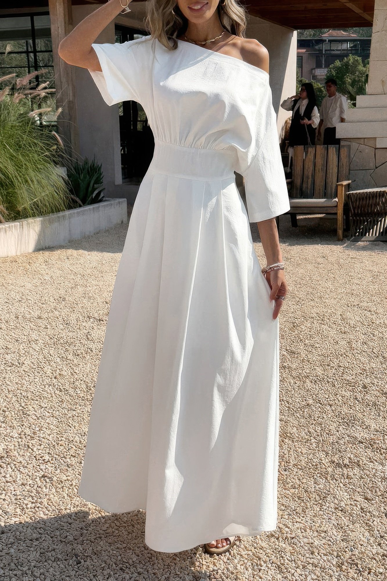 Woman wearing a white off-the-shoulder midi dress with wide sleeves
