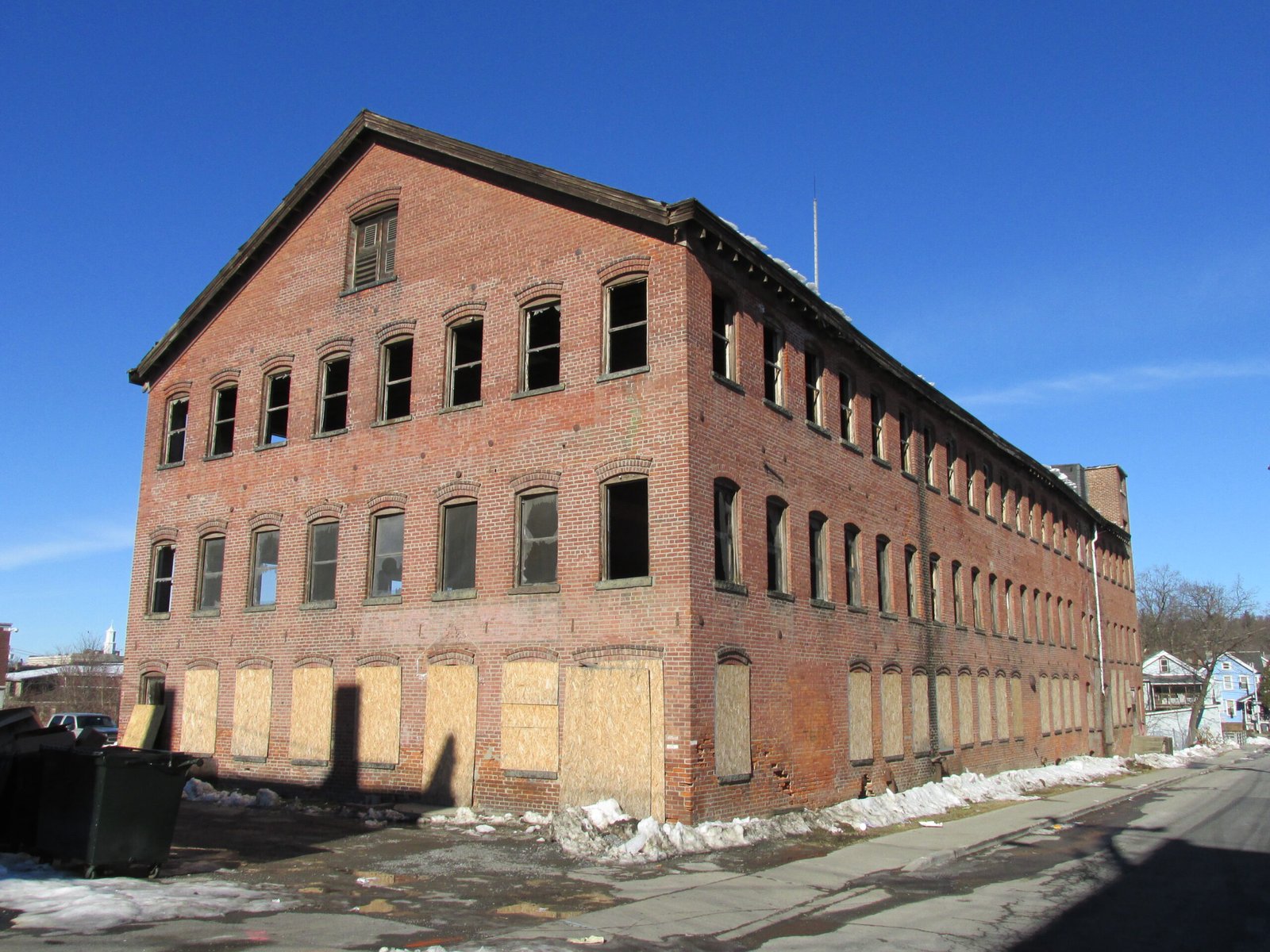 Exterior of an old brick factory building with boarded-up windows