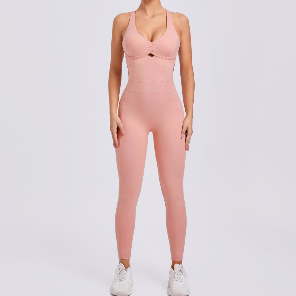 Woman wearing a pink yoga jumpsuit with a cutout detail