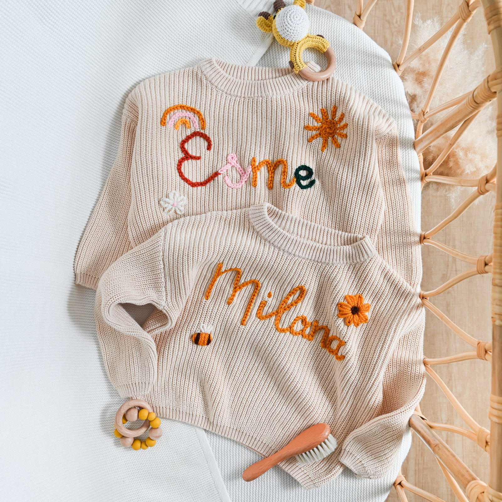 Two personalized knit baby sweaters with embroidered names and designs